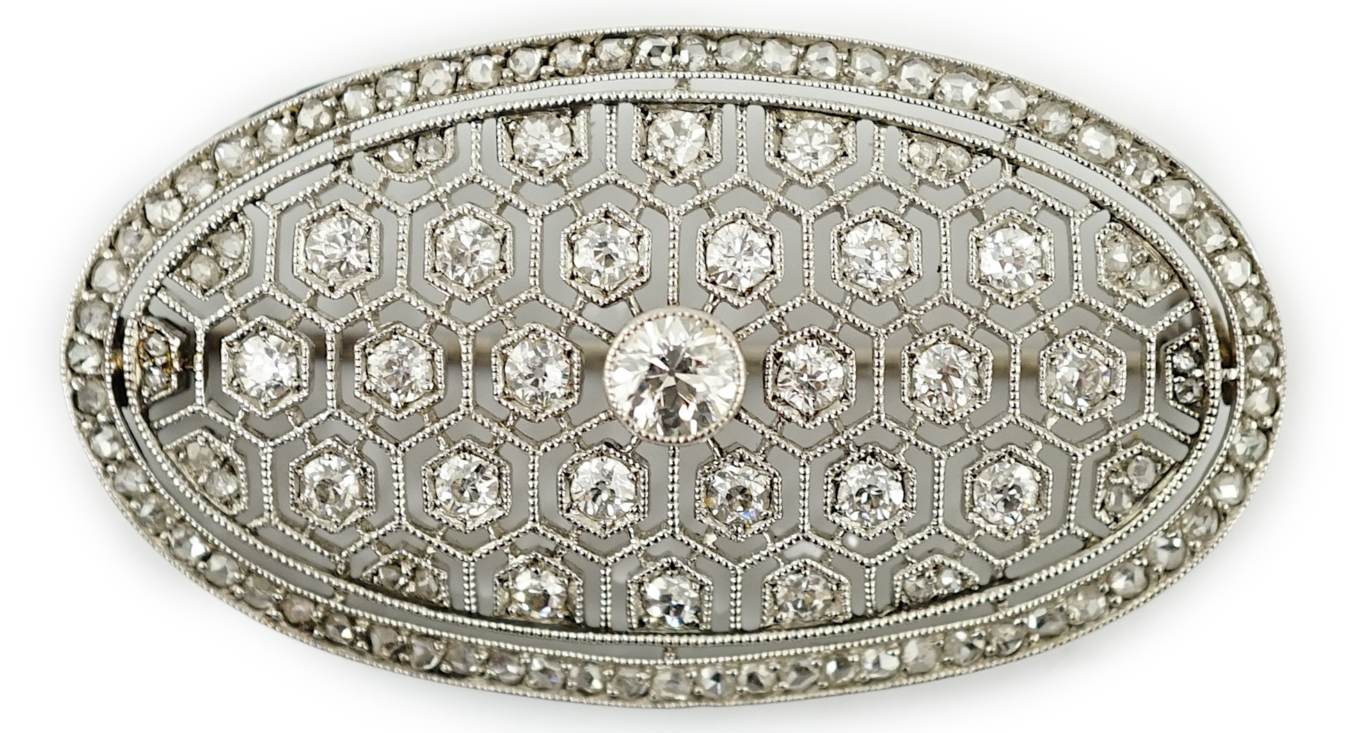 A Belle Epoque platinum and millegrain diamond cluster set oval brooch